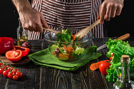鱼肉沙拉男人在木制桌上准备沙拉和新鲜蔬菜 烹饪美味而健康的食物饮食厨房萝卜厨师胡椒乡村木板午餐勺子黄瓜背景
