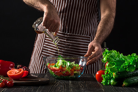 烹饪与家庭概念     特写男性手在碗里加橄榄油的沙拉行动围裙厨房成人男人木板盘子饮食蔬菜食物图片