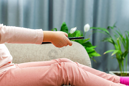 女孩在家里掌握电视遥控器的小女孩金发孩子闲暇按钮童年头发娱乐程序房子家园图片