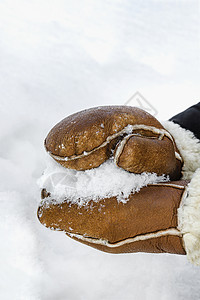 第一场雪 在公园特写镜头中制作雪球 冬天 戴着温暖手套的手会下雪 冬天雪地里的棕色皮手套图片