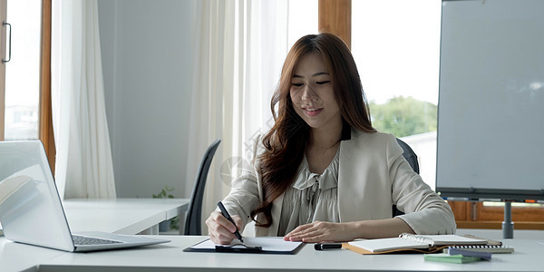 在她的工作站上使用笔记本电脑工作的亚洲年轻商业女性的肖像 商务人士员工自由在线报告营销电子商务电话营销概念经纪人经理人士企业家工图片