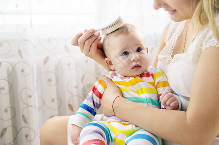 母亲正在梳小宝宝的头发 有选择地集中注意力家庭女性儿子生活妈妈女孩童年新生孩子刷子图片