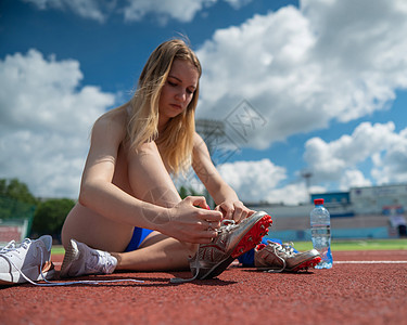 年轻的caucasian女子系鞋带 然后在体育场慢跑鞋类慢跑者女性耐力运动活动自由紧身衣蕾丝短跑图片