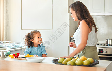 母亲和小女儿在说话 而妈妈教她如何做素食美食 用一个小帮手做饭图片