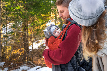 年轻父母与子女一起在户外 复制空间的婴儿穿婴儿冬季散步背景图片