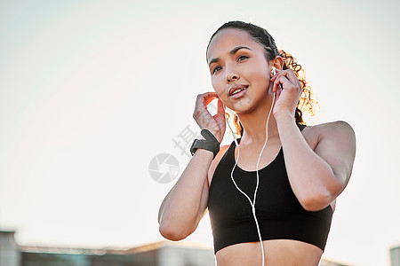 拍下一个有魅力的年轻女运动员 在城里跑步时 听音乐的场景 然后被剪辑图片