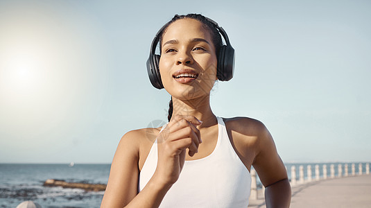 快乐的年轻健身女性穿着运动服 戴着无线耳机 一边沿着长廊跑步一边听音乐 锻炼有益于您的健康和幸福图片