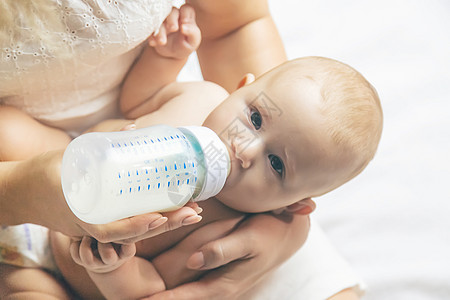 牛奶燕麦妈妈用瓶子喂婴儿 有选择的焦点后代微笑拥抱父母女性青年牛奶家庭食物新生背景