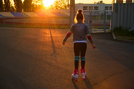 女孩在公园里骑滑雪鞋运动溜冰者乐趣溜冰鞋快乐体育场享受青年闲暇头盔图片