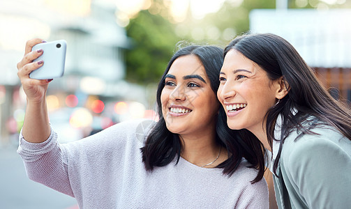 更少的竞争 更多的联系 两名年轻女商务人士在城市背景下用智能手机自拍的照片图片