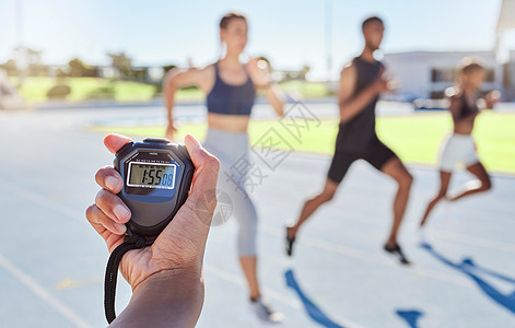 运动教练使用秒表为运动员计时 模糊的运动员冲向终点线并打破记录 秒表测量体育赛事马拉松比赛的时间图片