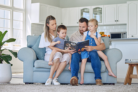 白人家庭在家里的沙发上一起看书 爸爸妈妈教他们的小儿子和女儿读书 兄妹和父母一起学习字母表图片