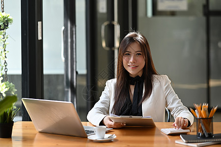 成功的女商务人士坐在办公室里 微笑着对镜头的笑容图片