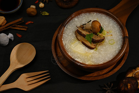 早餐或木桌上的轻餐用大米粥或加芝士蘑菇 切姜和菜煮饭背景图片