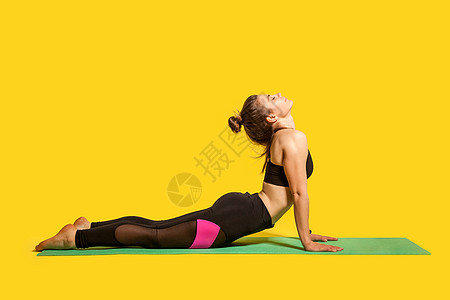 年轻女性在黄色背景的室内运动保健锻炼健身房眼镜蛇身体训练灵活性瑜珈裤运动员减肥图片