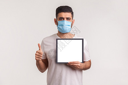 戴卫生面具的人举起大拇指 拿着白色海报 模型模板图片