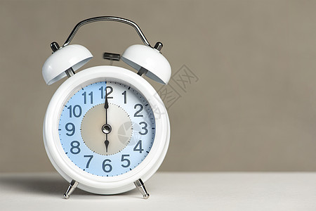 六点钟的闹钟 一个白色的闹钟在一张白色的桌子上 时钟指针指向 6 点 时间更改为夏令时或冬令时 设置 6 00 或 18 00 图片