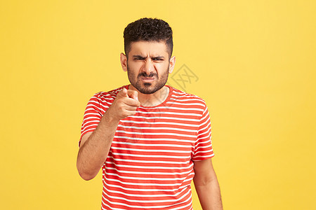 穿着红色T恤穿黄色背景的情绪年轻男子成人挫折男人挑战手指条纹眉头t恤胡子责备图片