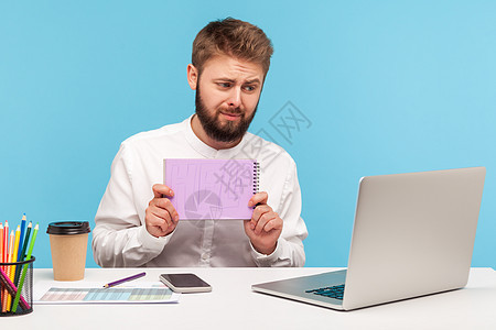 情感商务人士在蓝背景的笔记本电脑上工作电话记事本危机互联网压力眉头蓝色男人商务办公室图片