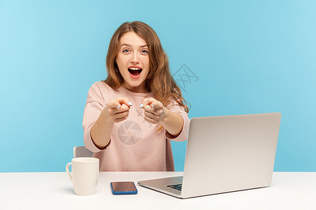 情感年轻女性在蓝背景的笔记本电脑上工作商务商业博主蓝色互联网女士手指办公室震惊检查员图片