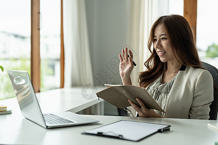 晚上 年轻的亚洲女性使用笔记本电脑与坐在办公桌前的同事在线观众进行视频通话 咨询 网络研讨会 互联网辅导 远程办公图片