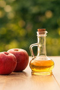 玻璃瓶中的苹果苹果醋和模糊背景的新鲜红苹果;以及图片