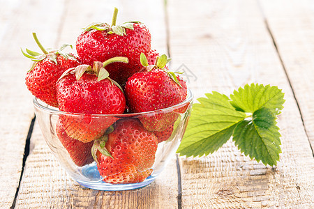 红熟的草莓 在旧木板上的玻璃碗里甜点植物绿色杯子叶子农场水果红色食物花园图片