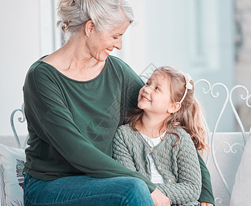 可爱的小女孩微笑着抬头看着她的祖母 坐在一起在家里亲密无间 向孙女表达爱意的美丽成熟白人女性图片