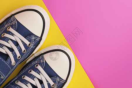 一对蓝运动鞋 在黄粉背景上橡皮帆布纺织品配饰青少年鞋类蕾丝潮人鞋带衣服图片