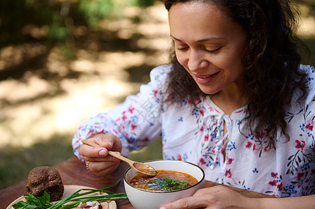 一位迷人的女士在室外吃甜菜根汤 食用美味的传统乌拉尼亚肉汤图片