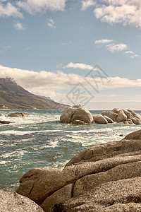 蓝色多云天空下海洋中的岩石 带有复制空间 在南非开普敦一个受欢迎的夏季地点 海滩海浪溅起巨石或大石头的风景钓鱼天空假期阳光飞溅热图片