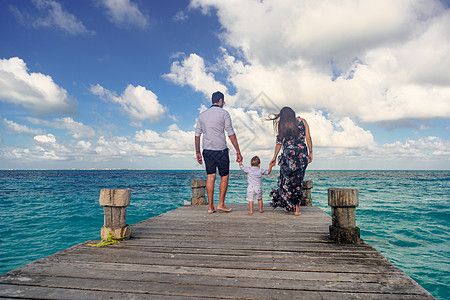 一个男人和一个女人带着一个孩子 在海边的码头散步图片