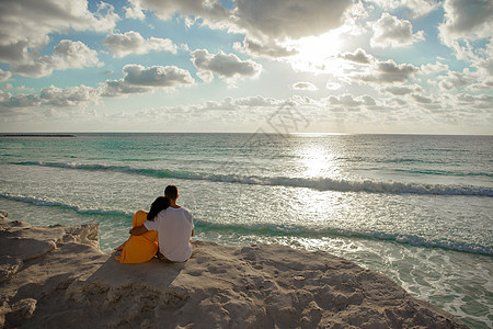 一男一女坐在海边 望着地平线天空拥抱蓝色男性日落家庭格子海滩岩石裙子图片