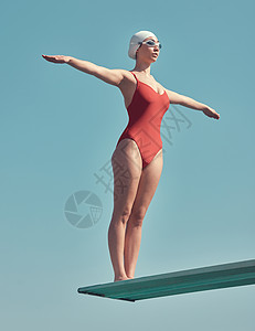 准备引起轰动 一位有吸引力的年轻女运动员站在外面的跳水板上的全长镜头图片