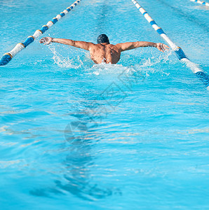 像蝴蝶一样移动 一个无法辨认的年轻男性运动员 在奥林匹亚大小的游泳池里游泳图片