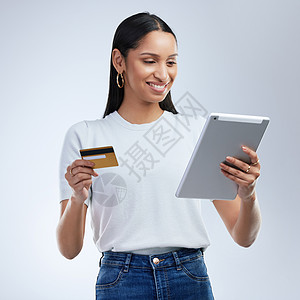 让您的财富增长的方法不止一种 一位女士拿着银行卡 在灰色背景下使用数字平板电脑图片