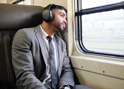 坐下来想了一会儿 一个年轻的商务人士在上下班途中戴着耳机凝视着窗外图片