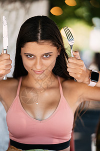 年轻美女拿着一把刀和叉子情感女孩微笑女士刀具女性饮食乐趣食物喜悦图片