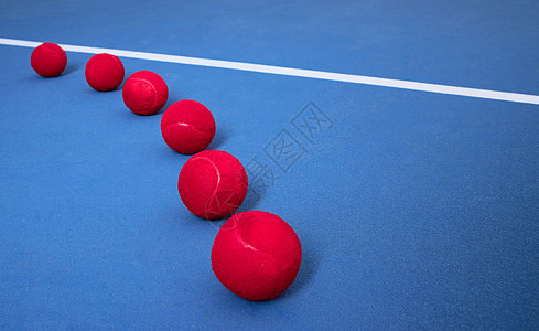 网球在蓝网球场上投下多个网球 而网球正在运动中图片