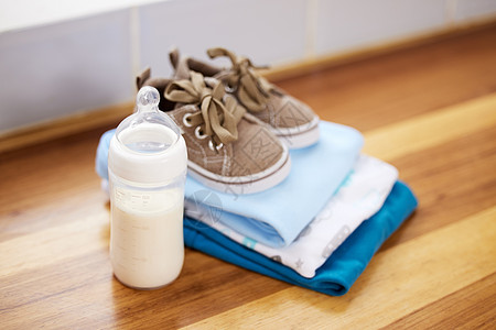 新的婴儿起步器包 婴儿衣服和奶瓶放在家里的桌子上图片