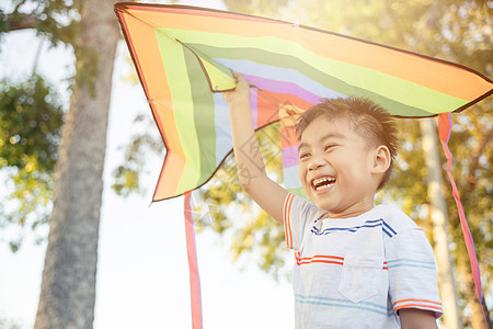 亚裔快乐的小孩男孩 带着风筝跑去公园飞男生乐趣自由场地天空童年太阳微笑草地跑步图片