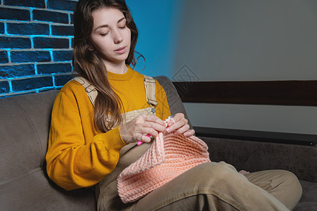 女孩坐在沙发上 用纱布编织毛衣 我们用厚的线织在一起 安居乐业钩针针织品纺织品手工女士工作工艺编织者针线活棉布图片