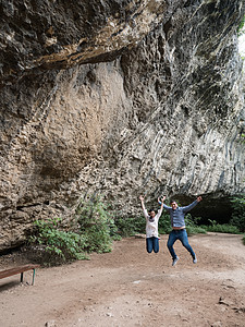 美丽的年轻夫妇在洞穴前 在幸福的空气中跳跃图片