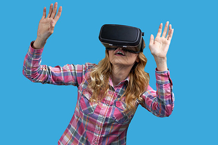 兴奋的女孩在蓝背景上使用虚拟现实头盔图片
