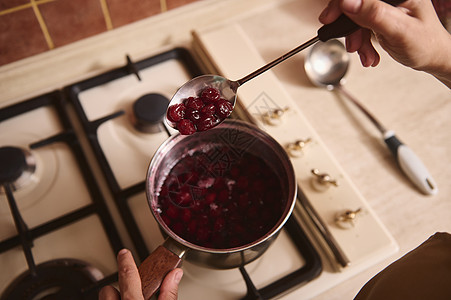 大厨甜食师双手的顶端风景 在烹饪自制的知觉时 搅拌开煮樱桃莓果酱加糖图片