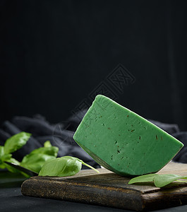 一块绿色芝士 黑色背景的棕色木板上含巴西尔小吃美食家食物产品叶子桌子奶制品牛奶早餐图片