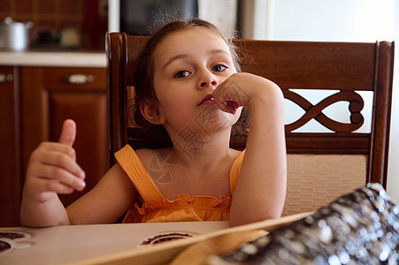 可爱的女童女孩坐在餐桌饭桌上 家里厨房内有自制樱桃派-修道院小屋图片