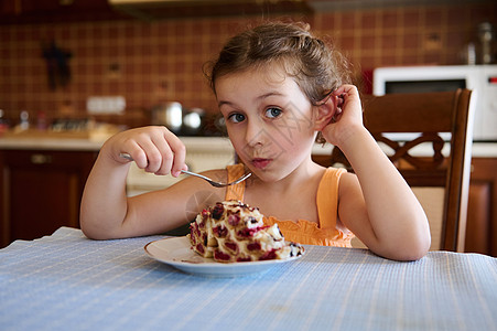 白种小女孩在家厨房吃着美味的自制樱桃蛋糕图片