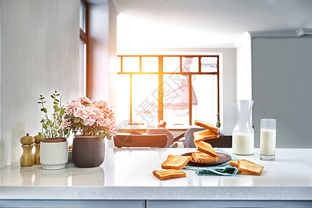 一杯牛奶和烤面包放在桌子上 厨房背景 太阳耀斑图片