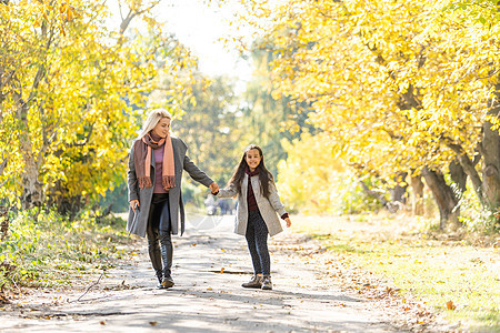 时装母亲和女儿 在秋天公园的一家人 穿大衣的小女儿叶子闲暇母性家庭裙子乐趣童年黑发喜悦成人图片